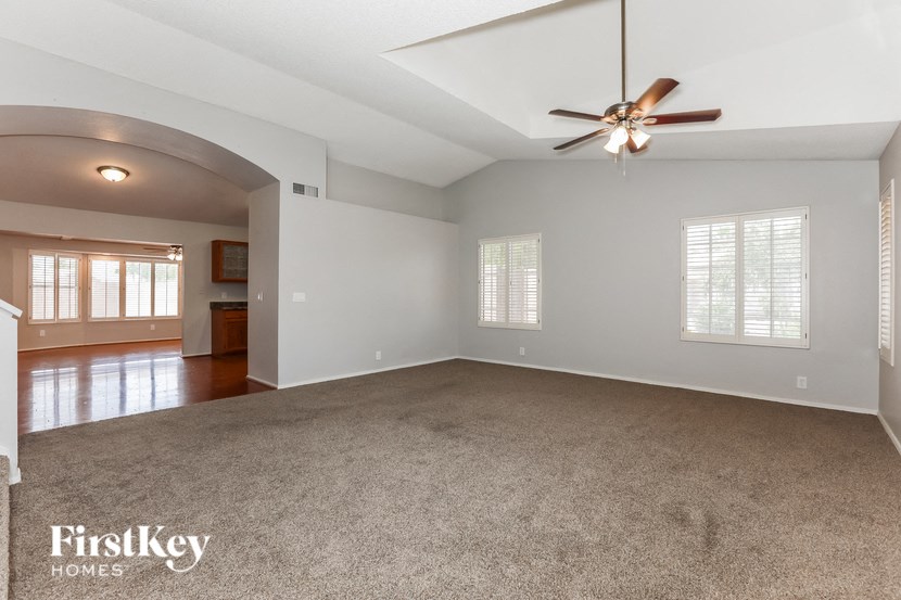 an empty living room with a ceiling fan and a carpet