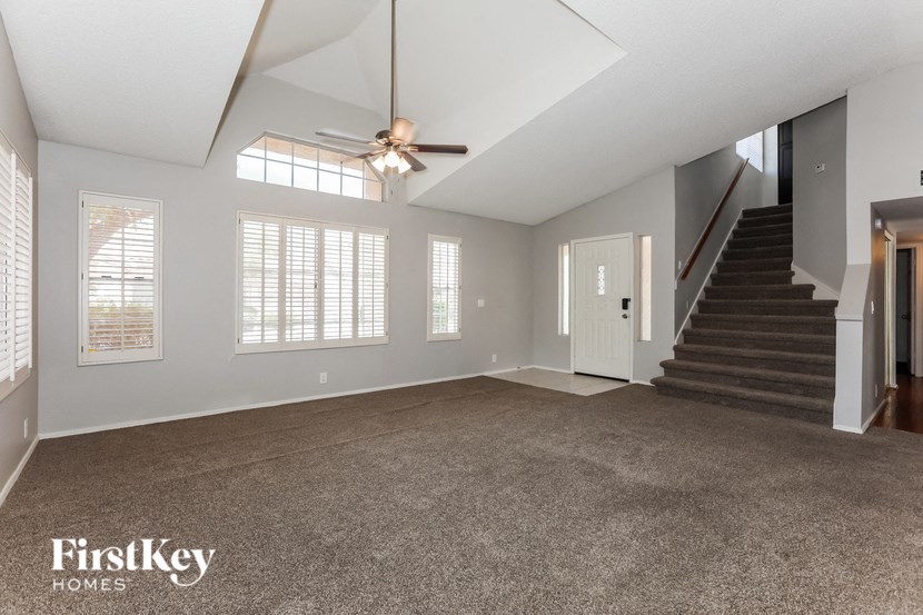 an empty living room with a ceiling fan and a staircase