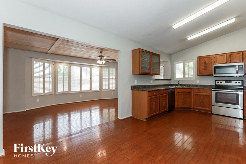an empty kitchen with wood flooring and a large window