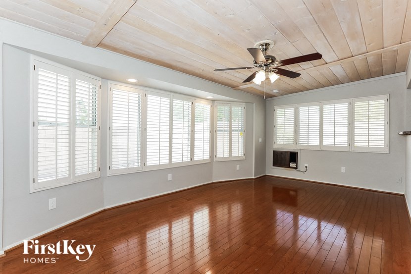 an empty living room with wood floors and a ceiling fan