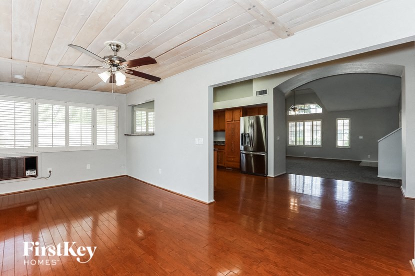 an empty living room with wood floors and a ceiling fan