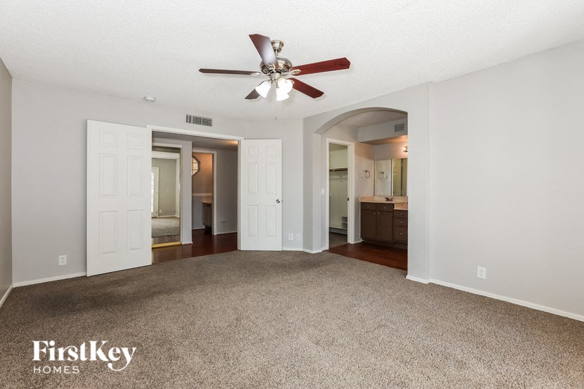 an empty living room with a ceiling fan and a carpet
