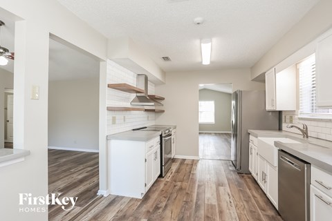 A kitchen with white appliances and wooden floors.