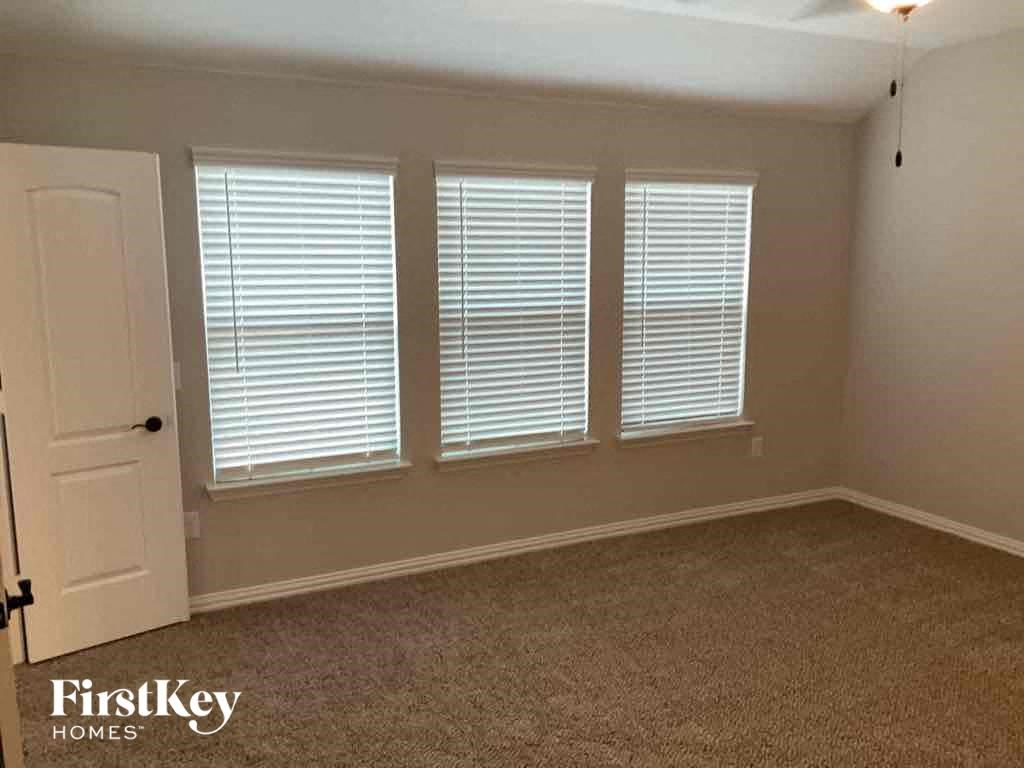an empty room with three windows and a white door