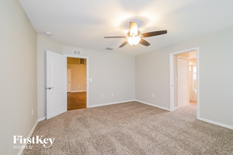 a spacious living room with carpet and a ceiling fan