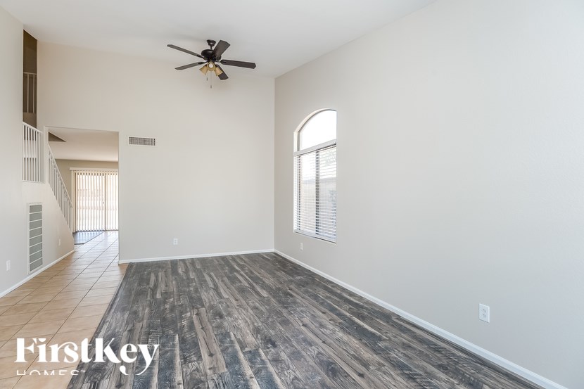 A spacious room with a wooden floor and a ceiling fan.