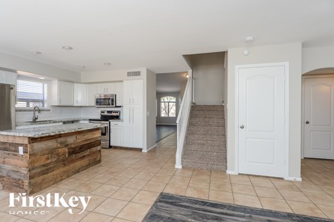 A kitchen with a wooden counter top and a staircase in the background.