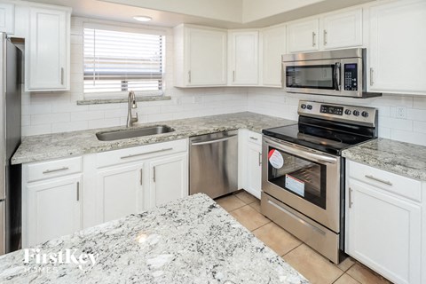 A kitchen with white cabinets and a granite countertop.