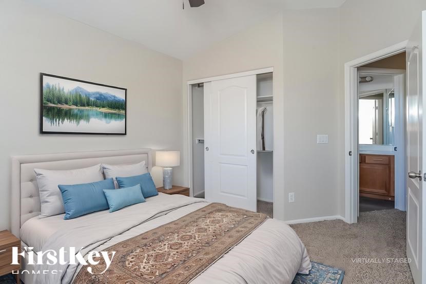 A bedroom with a large bed and a painting on the wall.