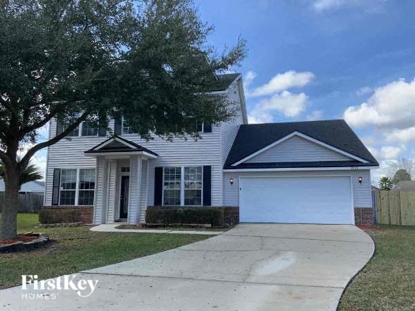 A house with a garage and a tree in front of it.