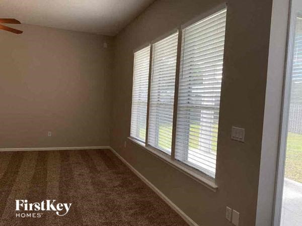 A room with a carpeted floor and a window with blinds.