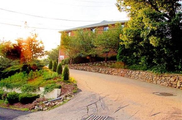 a street in front of a house with a stone wall