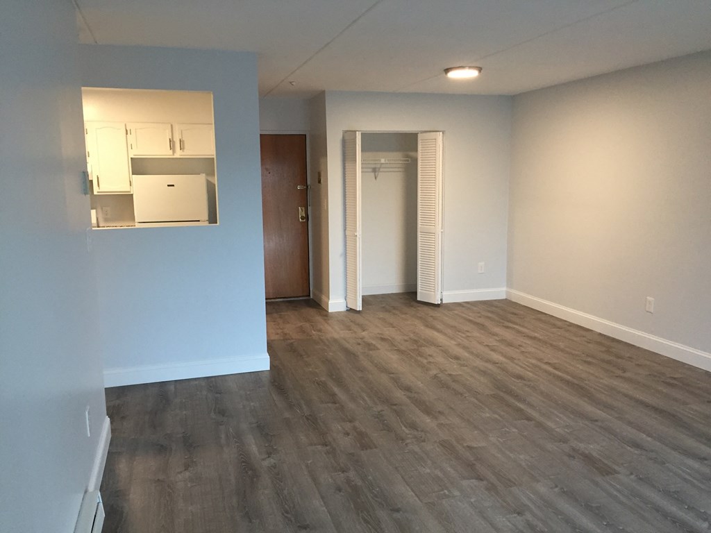 an empty living room with wood flooring and white walls