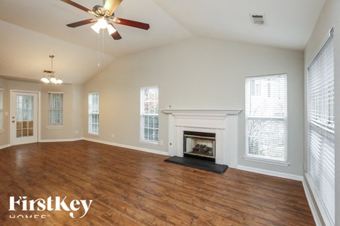 A spacious room with a fireplace and a ceiling fan.