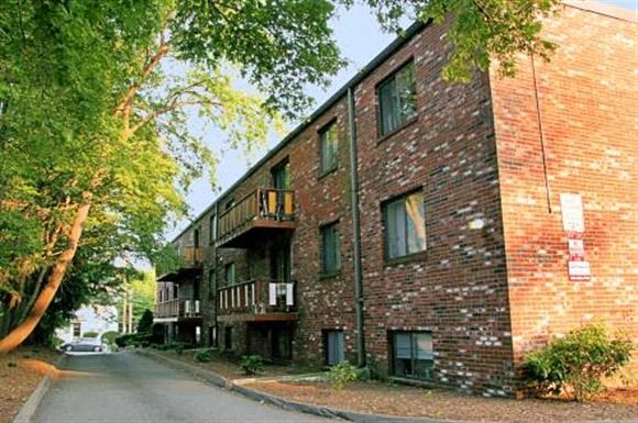 a brick apartment building with a street and trees
