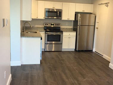 Renovated kitchen with granite counters, white cabinets and stainless appliances