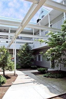 a large white building with trees and a sidewalk