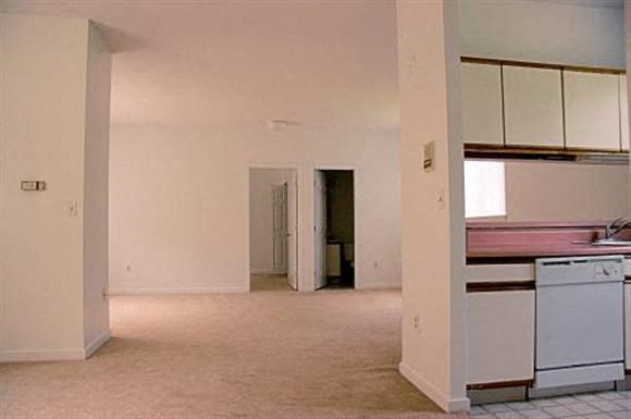 an empty kitchen with white cabinets and white appliances