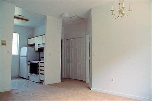 an empty living room with a kitchen and a door