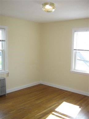 an empty room with a wood floor and two windows