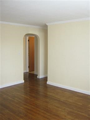 an empty living room with a wood floor and white walls
