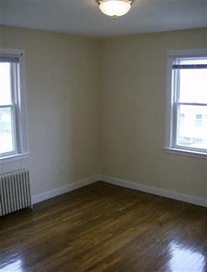 an empty room with a wood floor and two windows