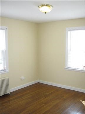 a living room with a wooden floor and two windows