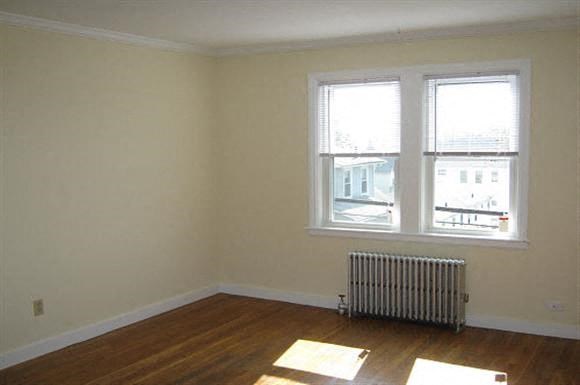 an empty room with a radiator and two windows