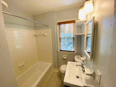 A bathroom with a white tub, sink, and toilet.