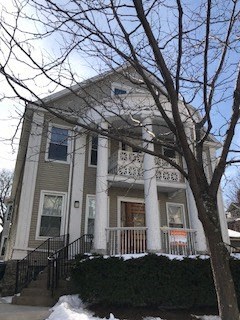 A house with a porch and a tree in front.