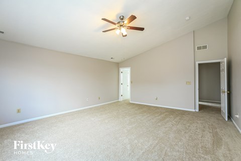 a spacious living room with white carpet and a ceiling fan