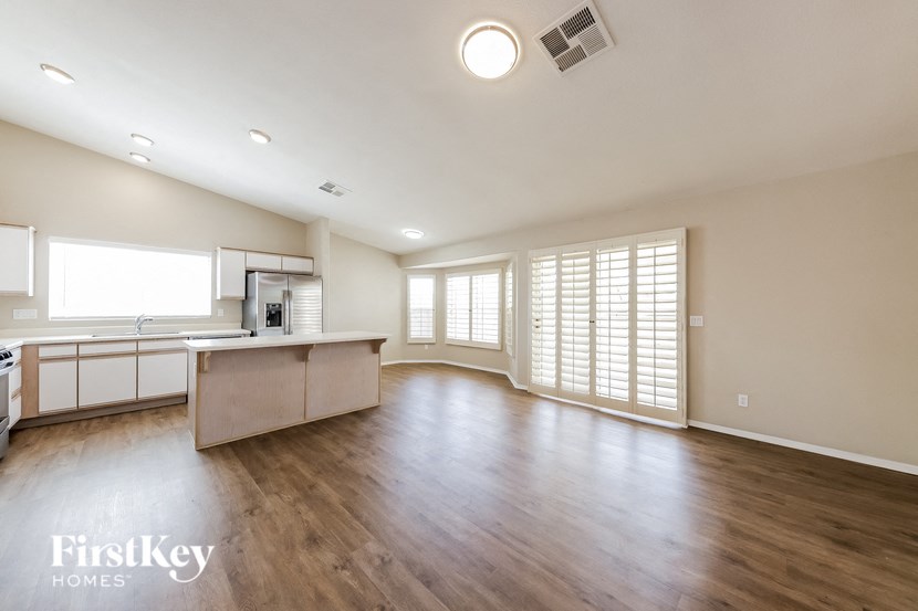 an empty living room and kitchen with wood flooring