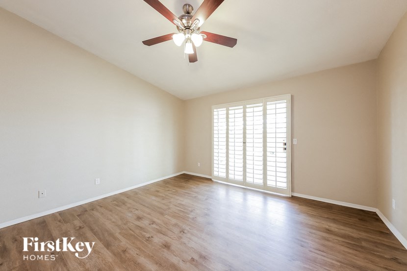 an empty living room with a ceiling fan and a window