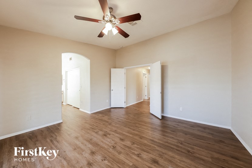 an empty living room with a ceiling fan and white walls