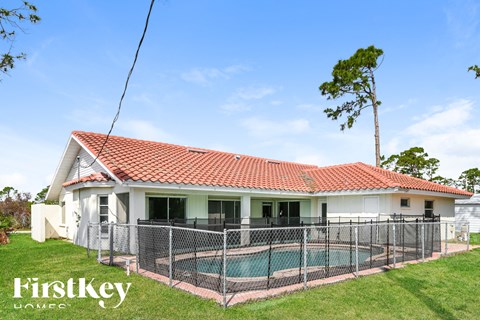 A house with a red tile roof and a pool in the backyard.