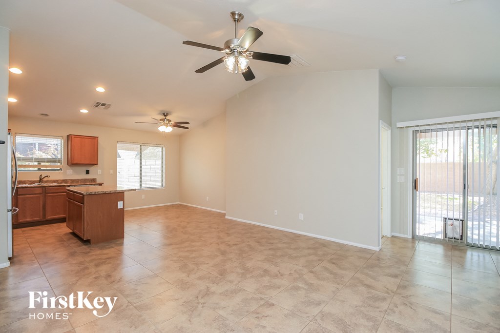 A spacious room with a ceiling fan and a kitchen area with wooden cabinets.