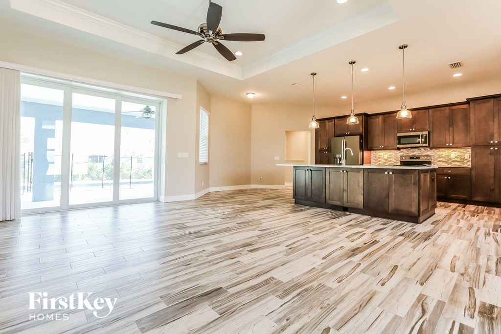 an open kitchen and living room with wood floors and a ceiling fan
