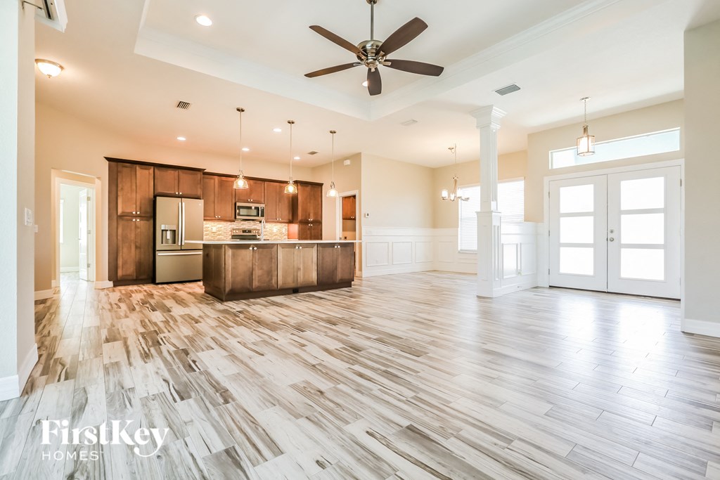 an open kitchen and living room with wood flooring and a ceiling fan