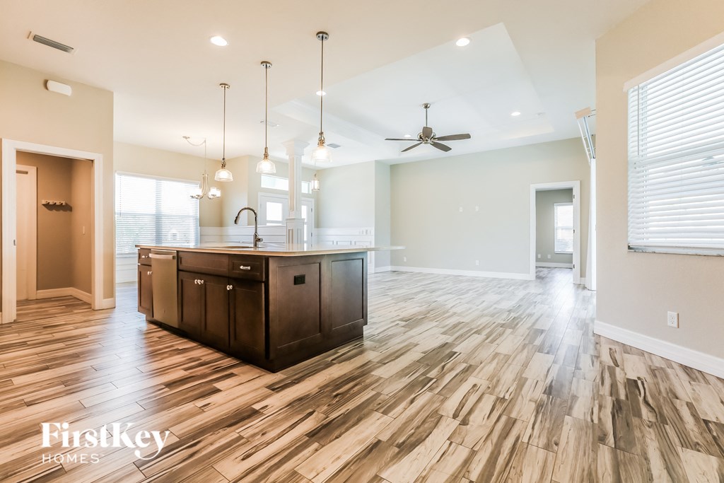 an open kitchen and living room with wood flooring and a ceiling fan