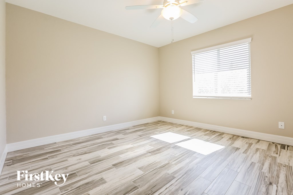 a spacious living room with hardwood floors and a ceiling fan
