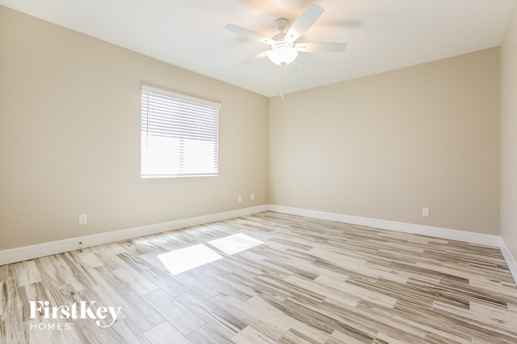a clean and empty room with a ceiling fan and a window