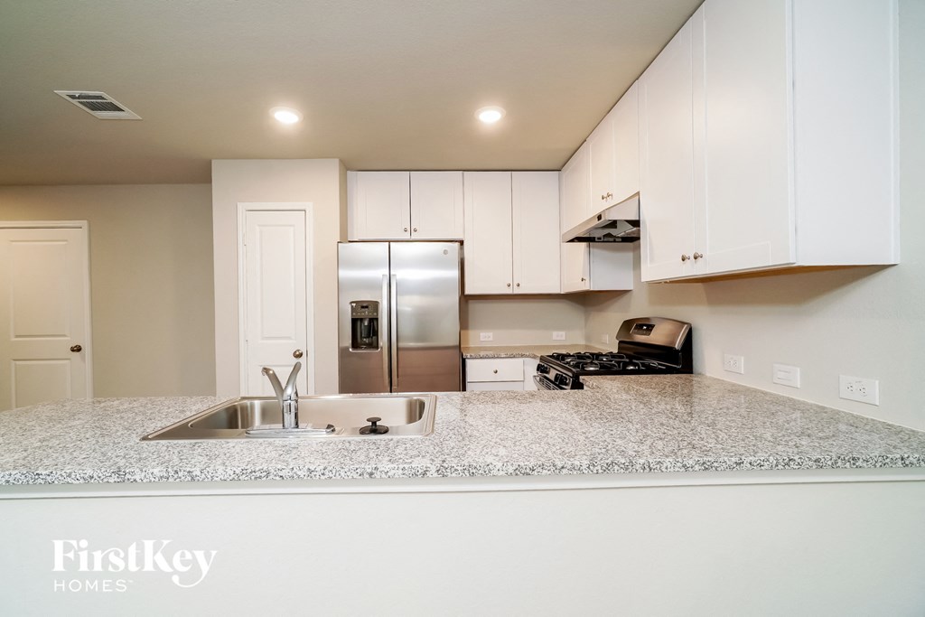 a kitchen with white cabinets and a granite counter top