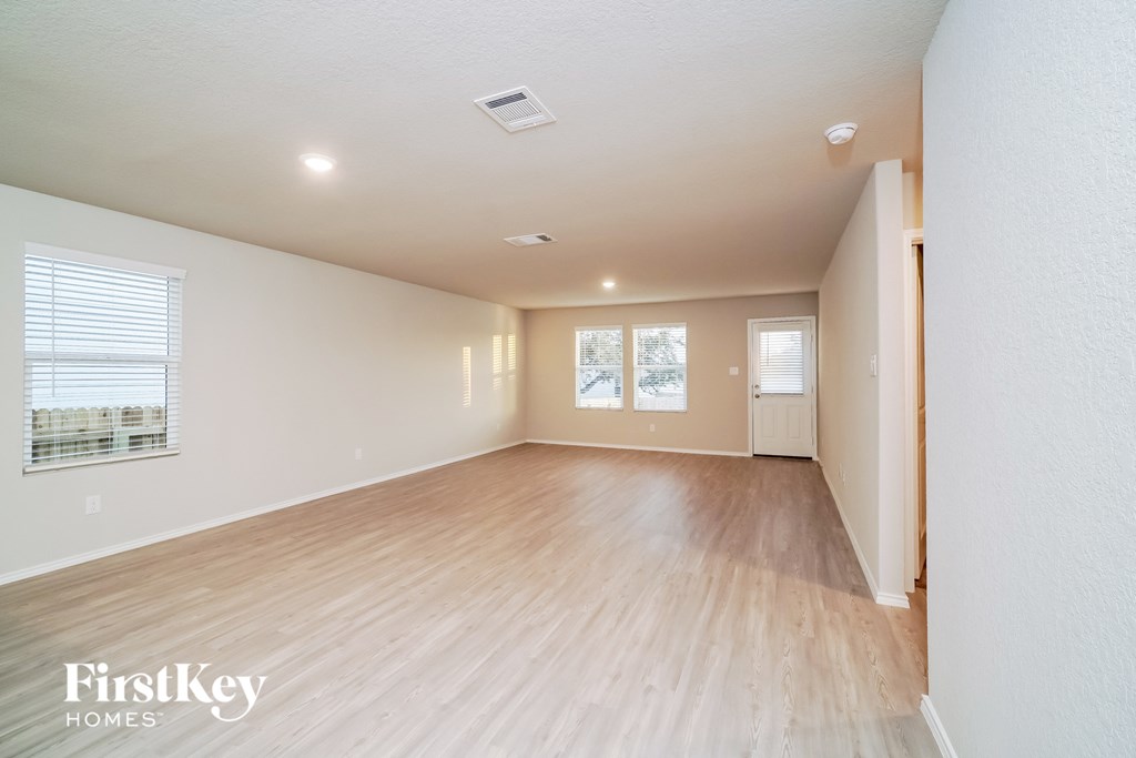 a spacious living room with wood flooring and white walls