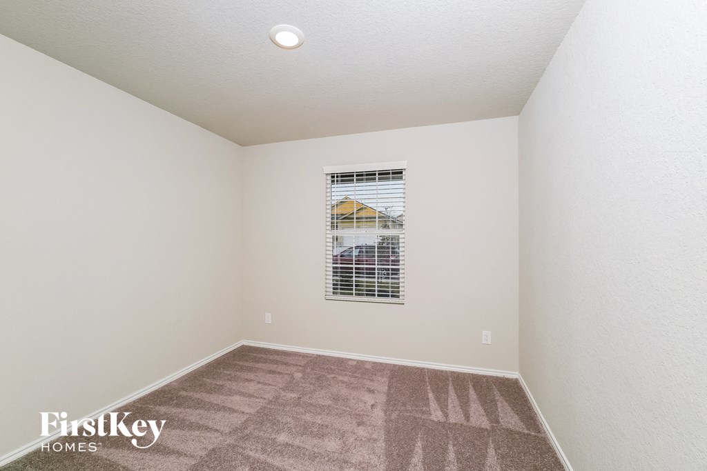 the living room of an empty house with carpet and a window