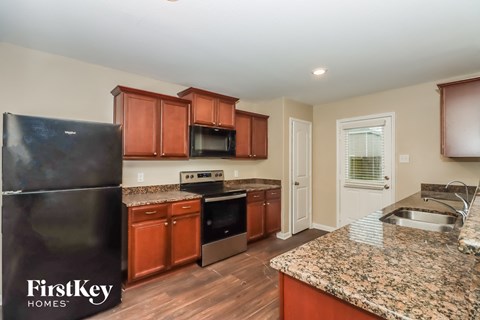 a kitchen with wooden cabinets and granite counter tops and a black refrigerator