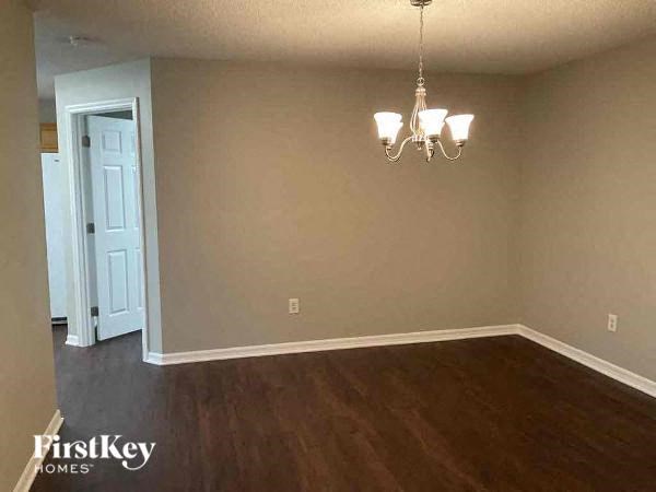 a empty living room with a chandelier and a white door
