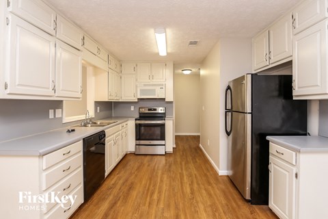 A kitchen with white cabinets and a black fridge.