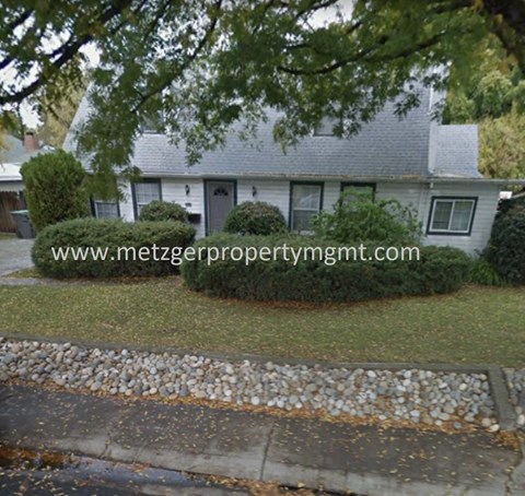 A house with a grey roof and a driveway with gravel.