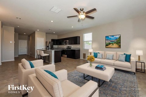 A spacious living room with a white sofa set and a ceiling fan.