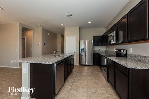 A kitchen with dark brown cabinets and a granite countertop.